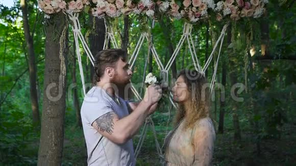 一对爱的夫妇在森林里的花拱附近视频的预览图
