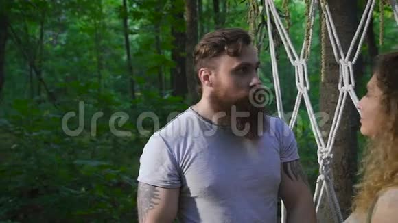 那个留着胡子的年轻人和他的女朋友在森林里的花拱附近视频的预览图