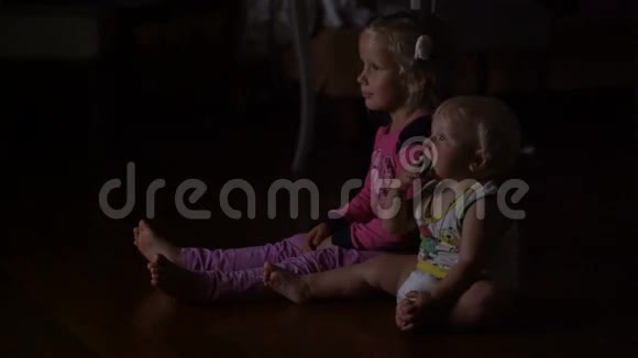 弟弟和妹妹坐在黑暗中看电视视频的预览图