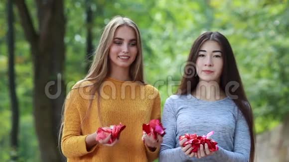 两个快乐的女朋友把玫瑰花瓣扔在顶端视频的预览图