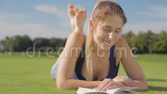 一位微笑的年轻女子在公园放松读一本书视频的预览图