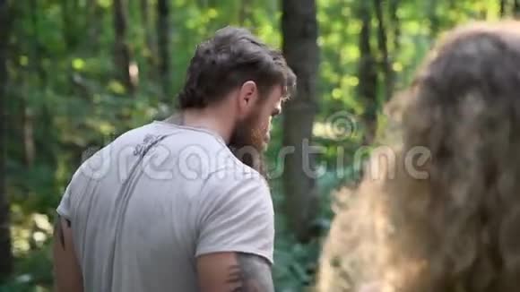 一个留胡子的男人和他的女朋友在树林里散步他们聊天他看着她微笑视频的预览图