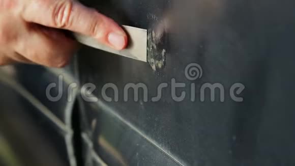 一个人用刮刀清理汽车上的铁锈视频的预览图