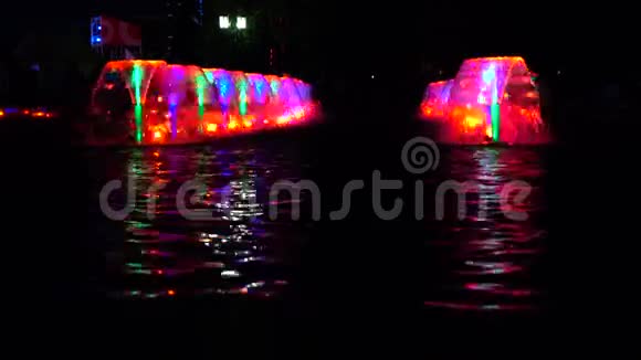 夜间LED点亮多色喷泉反射水波纹4K视频视频的预览图