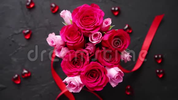 粉红色玫瑰花束装在红色盒子里放在黑色的石头背景上视频的预览图