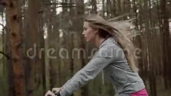 一个穿灰色运动服的金发女郎骑自行车一个穿灰色运动服的金发女郎骑自行车视频的预览图