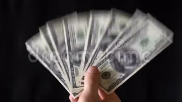 镜头中的手在黑色背景上挥舞着美元钞票视频的预览图