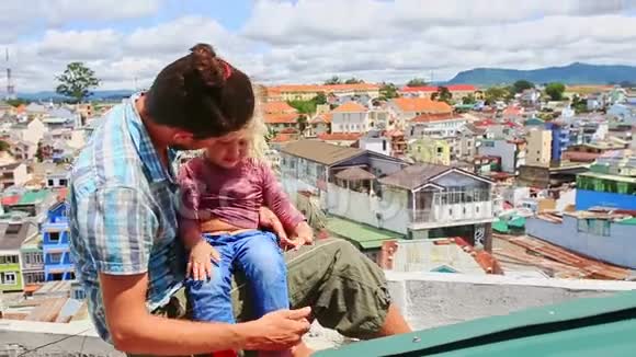 亲密的父亲小女孩坐在高屋顶靠城市视频的预览图