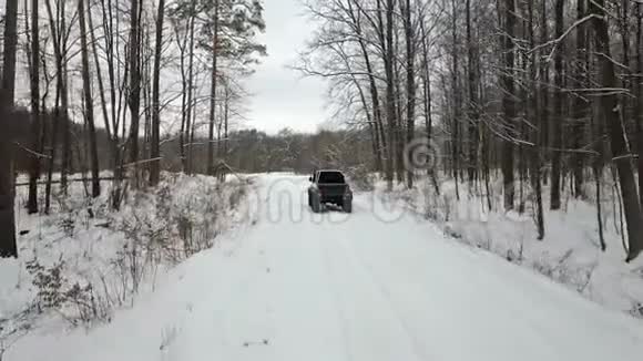 越野车6x6在冬季森林中的雪覆盖道路上行驶后视视频的预览图