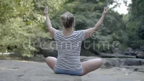 女孩坐在岩石上的姿势放松视频的预览图