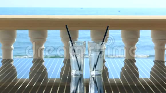 餐厅桌上两杯水加冰俯瞰大海在海浪的背景下副本视频的预览图