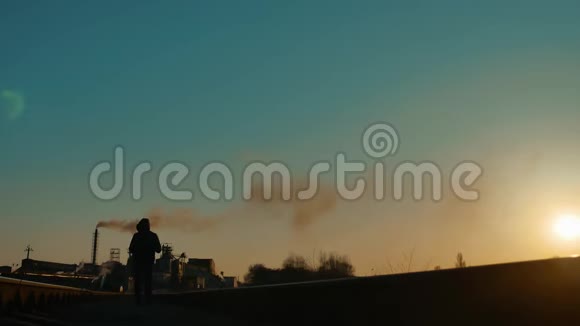 流浪者徒步旅行者在铁路剪影路旁行走一个背着背包去看日落的人视频的预览图