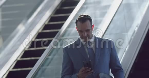 在现代化办公室4k自动扶梯上使用手机的商人视频的预览图