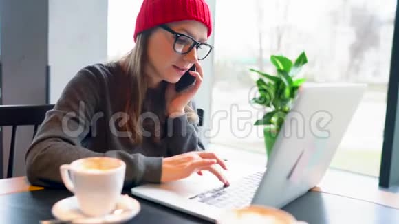 一位年轻漂亮的女士在咖啡馆的智能手机上工作和说话视频的预览图