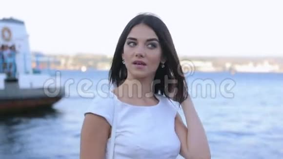 美丽的黑发女郎站在海边的码头上身着白色礼服视频的预览图