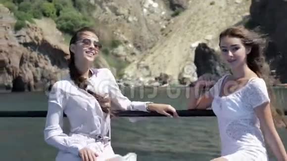 坐在船上的两个漂亮的模特儿穿着白色的小礼服视频的预览图