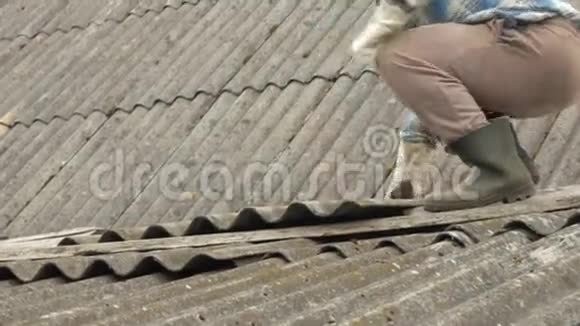 一位老人正在自己修屋顶石板上的旧木屋视频的预览图