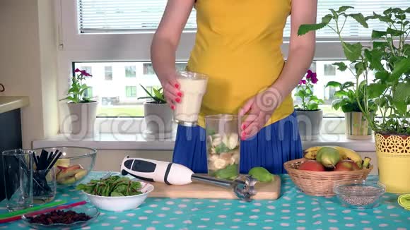 在厨房里把牛奶鸡尾酒和水果混合在一起的孕妇视频的预览图