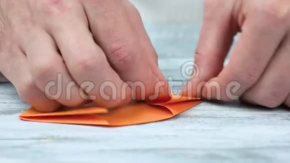 双手从橙色的纸上折折纸视频的预览图