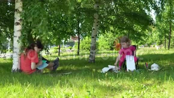 妈妈和女儿在树荫下的公园里从事创造力视频的预览图