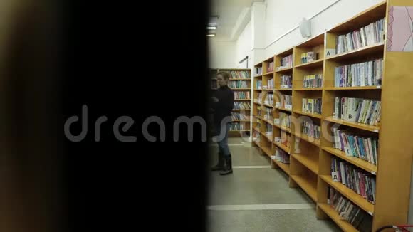 女人正在图书馆看书她在书之间的走廊里视频的预览图