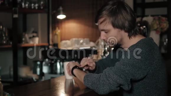 年轻时尚的男人在咖啡馆里检查他的智能手表喝咖啡视频的预览图