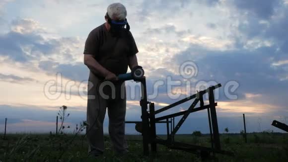 一个年纪大的人在日落时切断了一个金属角磨床工人后面美丽的天空视频的预览图