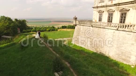 鸟瞰年轻的新婚夫妇在城堡的下降4k视频的预览图