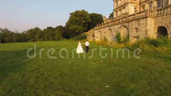 鸟瞰图一对新婚夫妇走在古堡前的背影4公里视频的预览图