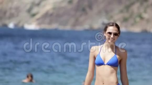 穿比基尼和太阳镜的可爱女孩靠近大海视频的预览图