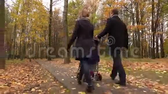 年轻的一家人和婴儿车在秋天公园散步4克斯泰德姆视频的预览图