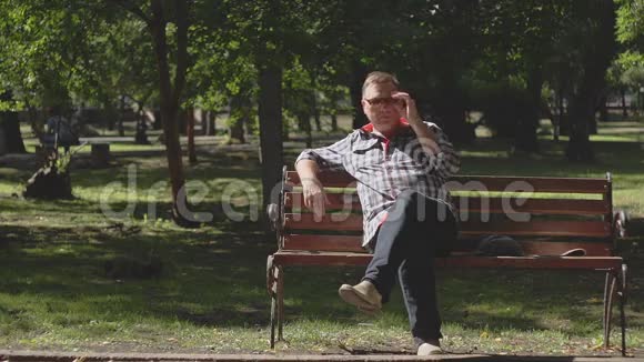 一位老人在公园的长凳上看报纸视频的预览图