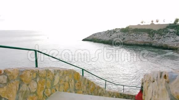 穿红色裙子的浪漫女孩走在海边的楼梯上视频的预览图