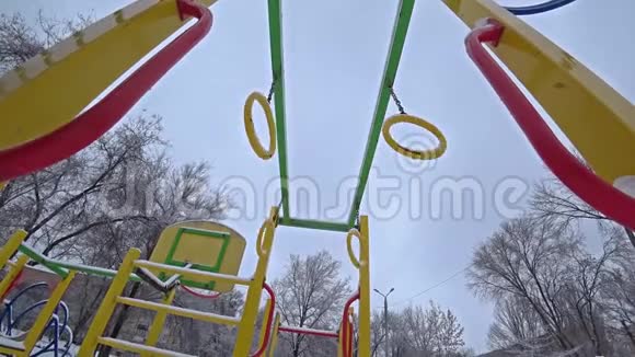 空孩子在阳光明媚的冬日在城市公园的操场上摇摆从底部看背光视频的预览图
