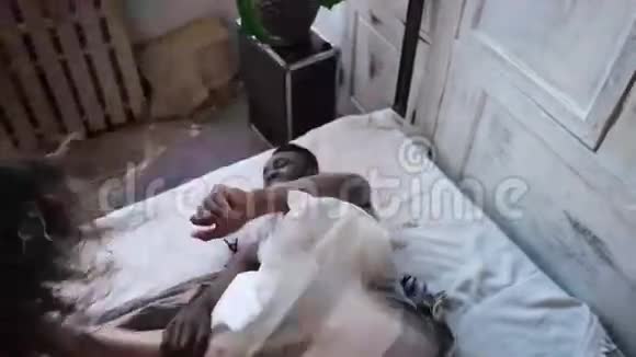多种族的情侣躺在床上靠枕头打架穿着睡衣的女人和男人在家里度过闲暇时光视频的预览图