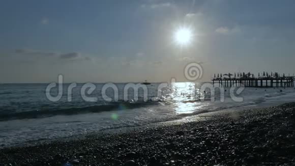 海岸上的一个木制码头人们游泳享受海浪暴风雨的大海和美丽的日落视频的预览图