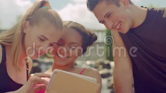 快乐的朋友在户外平板电脑上上网年轻人玩得开心视频的预览图