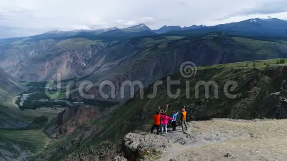 一群朋友高兴地爬上了山顶他们拥抱和跳跃回头望向远方视频的预览图