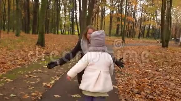 小女孩在秋天公园向妈妈跑去快乐的人拥抱落叶背景4Ksteatam视频的预览图