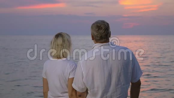 日落时分在海边微笑的老夫妇视频的预览图