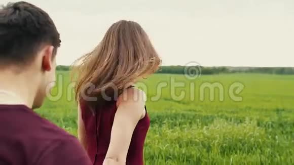 恋爱中的年轻夫妇一个男人正在跟踪他的女朋友牵着她的手走在一片田野里慢莫稳定射击视频的预览图