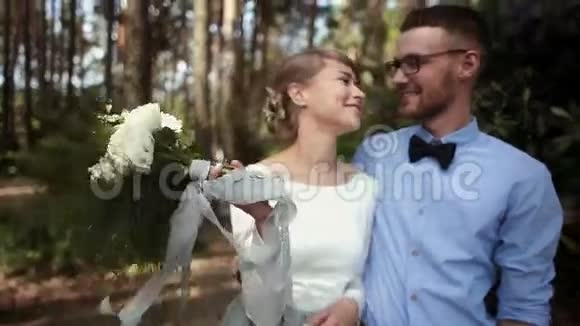 年轻漂亮的一对新婚夫妇在公园的绿树下接吻视频的预览图