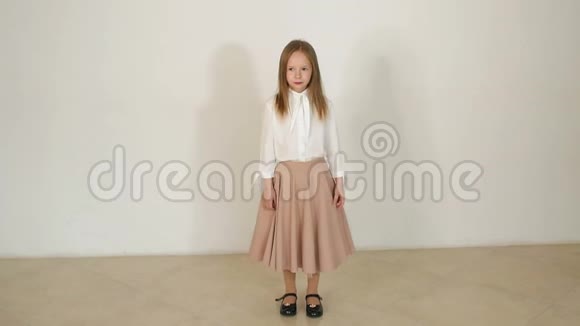 一个穿着漂亮长裙的小女孩在一个白色背景的工作室里摆姿势视频的预览图