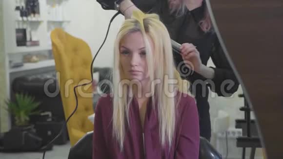 女理发师在美容院用卷发熨斗卷发视频的预览图