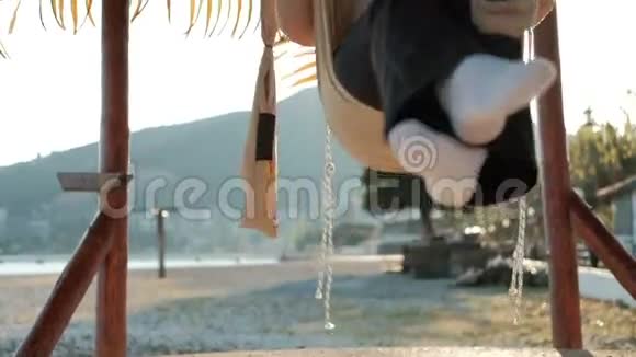 慢镜头拍摄摇摆女人在纸巾米色摇摆在岸上视频的预览图