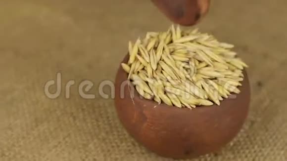 用勺子把一个旋转的陶罐里的燕麦粒倒掉视频的预览图