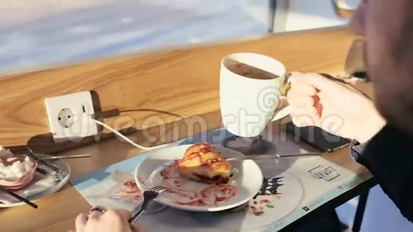 年轻人吃牛角面包在城里的咖啡馆里喝咖啡慢分子视频的预览图