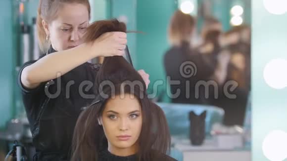 美容院化妆师为有魅力的女孩做发型特写视频的预览图