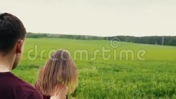 恋爱中的年轻夫妇一个男人正在跟踪他的女朋友牵着她的手走在一片田野里慢莫稳定射击视频的预览图