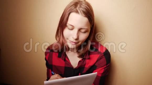 可爱的女孩写日记坐在家里的沙发上黄昏4KUHD视频的预览图
